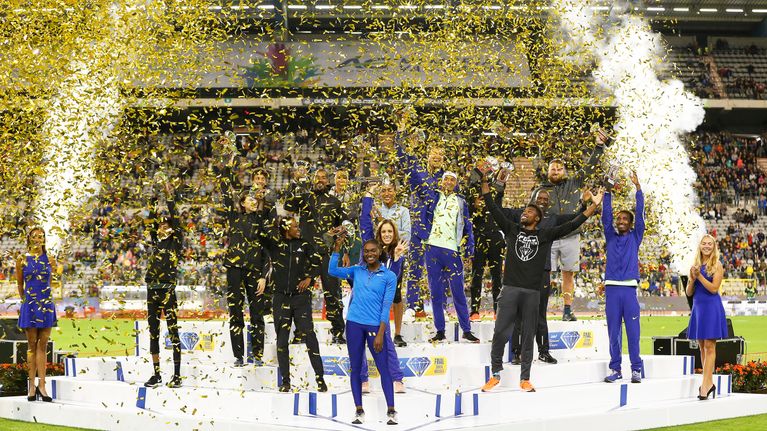 Urheilijat seisovat palkintokorokkeella stadionilla ilotulitusten ja kultakonfettien keskellä.