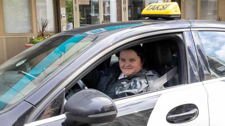 A woman taxi driver looks out of her car.