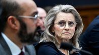 Päivi Räsänen, with blonde hair, eyeglasses and a black top, looking to the left, at a man with a dark beard speaking into a microphone.