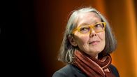 Anne Carsonilla on keltaiset silmälasit. Taustalla on tumma verho.