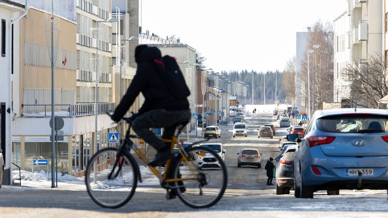 Pyöräilijä ylittämässä suojatietä kaupungin keskustassa.