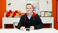 Henkilö istuu pöydän ääressä, taustalla näkyy Angry Birds -aiheisia koristeita ja julisteita.