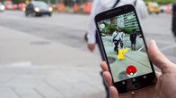 Matkapuhelimen ruutu, jolla Pokémon Go -peli lisättynä katumaisemaan.
