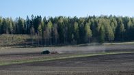 Traktori kyntää laajalla peltoaukeamalla.