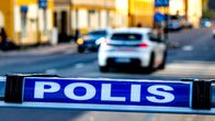 En skylt med texten "polis" och en polisbil i bakgrunden.