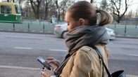 Kvinna går på stan och kollar på sin smarttelefon.