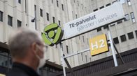 Arbetsförmedlingsbyråns skylt med en man med munskydd i förgrunden