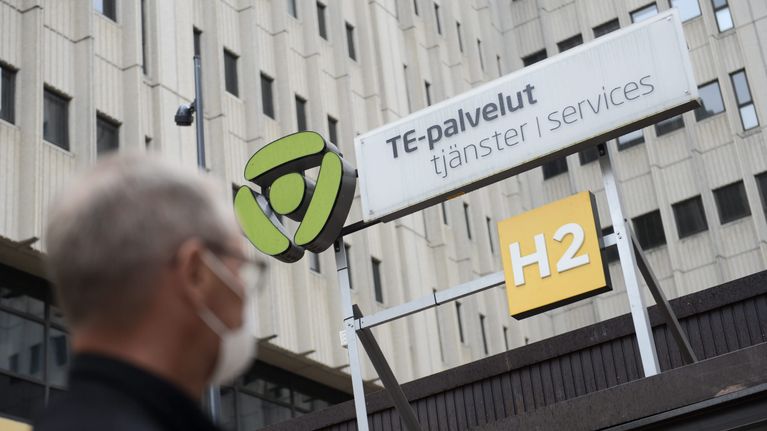 Arbetsförmedlingsbyråns skylt med en man med munskydd i förgrunden