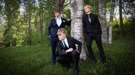 Yläkoululaiset poseeraavat koivun ympärillä pukeutuneina tummiin pukuihin.  