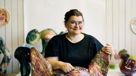 Henkilö istuu värikkään ja taiteellisen veistoksen päällä, ympärillä on muita värikkäitä teoksia. 