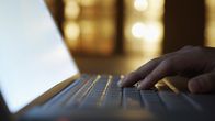 A hand on a laptop keyboard.