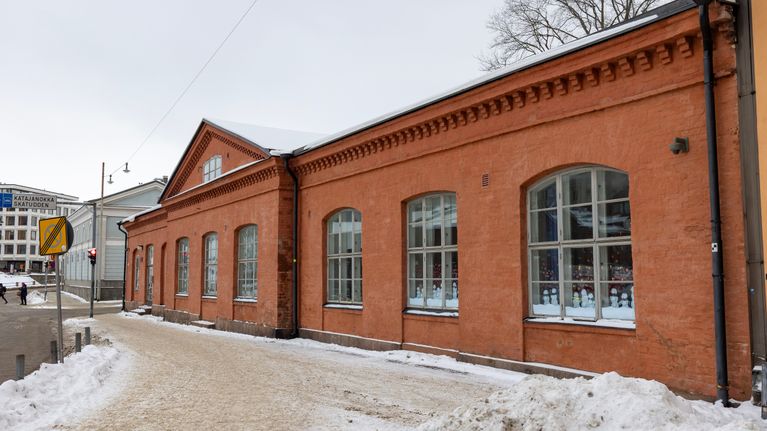 Yksikerroksinen, punatiilinen vanha rakennus.