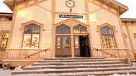 Oulun puisen rautatieaseman sisäänkäynti, ja matkustaja menossa sisään taloon.