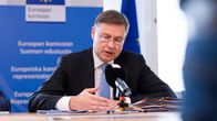 Valdis Dombrovskis puhuu medialle pöydän ääressä.