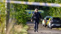 Polis som promenerar på en sandväg i naturmiljö, i bakgrunden syns en ambulans.