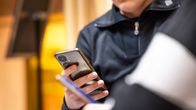 Två anonyma ungdomar scrollar på sina telefoner. 