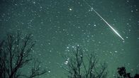A bright meteor streaks across the night sky.