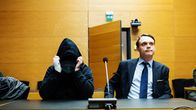 Kasvonsa huppuun piilottanut syytetty ja hänen asianajajansa oikeussalissa.