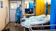 Suojavarusteisiin pukeutunut lähihoitaja Janina Kinnunen koronapotilaan kanssa.