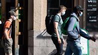 Ihmisiä kiirehtii junalta kasvomaskeihin suojautuneena Helsingin rautatieasemalla.