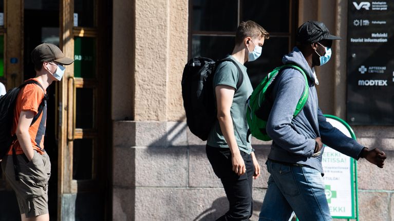 Ihmisiä kiirehtii junalta kasvomaskeihin suojautuneena Helsingin rautatieasemalla.
