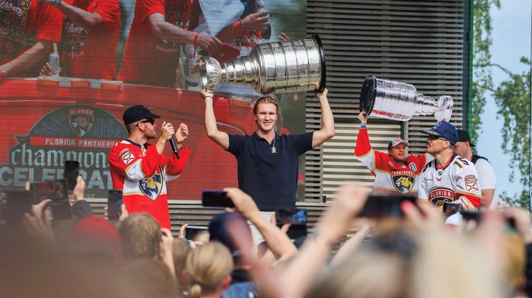 Anton Lundell nostaa Stanley Cup -pokaalin ilmaan Linnanmäen ohjelmalava Estradilla. Lavalla on myös JVG-yhtye.