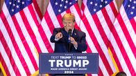 Donald Trump osoittaa sormellaan yleisöön puhujankorokeelta lavalta. Taustalla Yhdysvaltain lippuja.