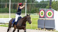 Nainen ampuu jousella hevosen selästä maalitauluun.
