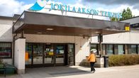 Nainen on menossa Jokilaakson sairaalan ovesta sisälle, taivaalla on tumma pilvi.