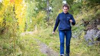 Siniasuinen nainen kävelee polkua alaspäin.