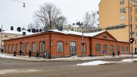 Yksikerroksinen, punatiilinen vanha rakennus.