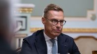 Alexander Stubb wearing a blue suit sits behind a microphone. 