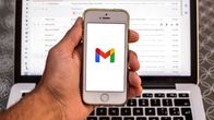 Henkilö pitää puhelinta kädessä ja puhelimen näytöllä näkyy Googlen gmail palvelun logo.