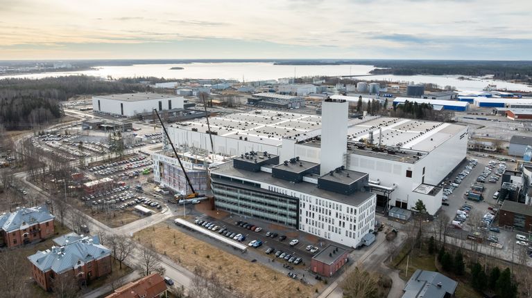 Wärtsiläs fabriksutrymmen på Vasklot fotograferade från luften. Man ser massiva byggnader i vitt, parkeringsplatser runtom och havet vid horisonten.