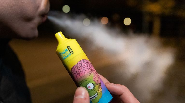 Värikäs Vape kädessä ja suusta tulee höyryä.