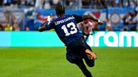 Jalkapalloilija juoksee kentällä sinisessä peliasussa, selässään nimi "Lopes Cabral" ja numero 13. Taustalla mainostauluja ja katsojia.