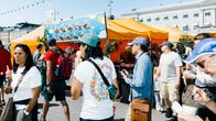 People, some eating ice cream, at an outdoor market on a sunny summer day in Helsinki.