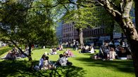 Människor sitter i en park i Helsingfors och njuter av solen.