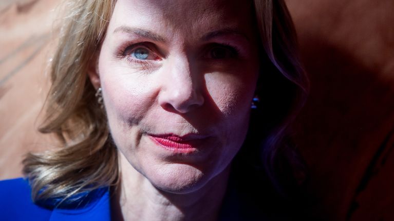 Anu Bardford seisoo seinään vasten sinisessä bleiserissä.