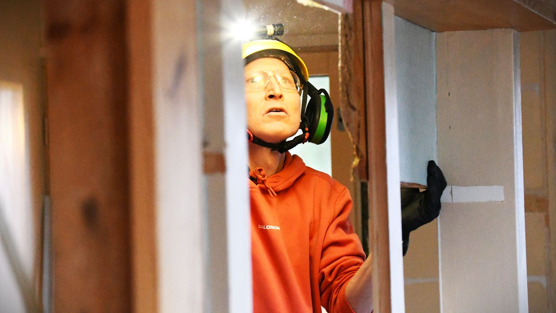 Orienteraren Mårten Boström i skyddshjälm och -glasögon renoverar ett gammalt hus.