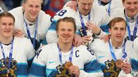 Six men in white-and-blue jerseys, most of them smiling, with bronze medals hanging from their necks.