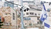 Useita valvontakameroita tolpassa, ja Israelin lippu taka-alalla.