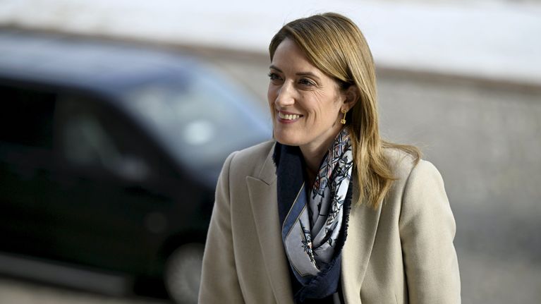 Euroopan parlamentin puhemies Roberta Metsola kuvattuna nousemassa portaita, huivi kaulassaan, vaalea jakku päällään.