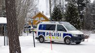 Kaksi poliisiautoa keltaisen hirsitalon edessä talvisena lumipäivänä.