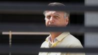 Bolsonaro ser ut genom något som liknar galler, men som sannolikt är någon typ av staket. 