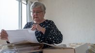 Sirkka Kukkonen katselee vanhoja valokuvia ja paperisia asiakirjoja.