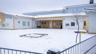 Aidattu päiväkodin piha, jolla hiekkalaatikko ja mäenlaskuvälineitä.