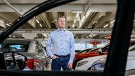 Henkilö seisoo autokaupassa autojen keskellä.