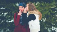Tyttö kuiskaa toiselle tytölle jotain