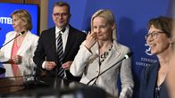 Four party leaders in suit jackets behind podium at press conference, all with half-smiles. Orpo second from the left, flanked by three women.